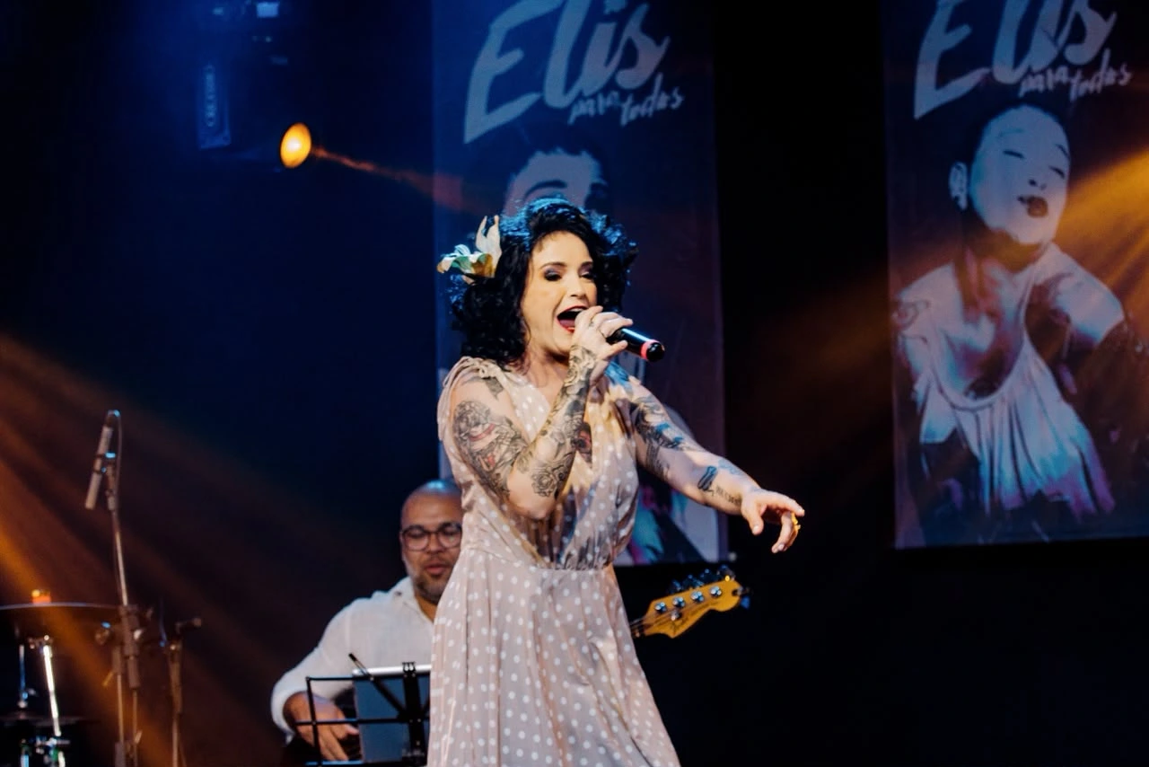 Apresentação ao vivo em auditório com músicos e plateia assistindo ao tributo a Elis Regina